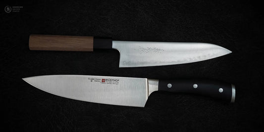 Two chef's knives on black background: Yoshihiro gyuto with wooden handle, and Wüsthof Classic with black western handle. Contrasting Eastern and Western kitchen knife designs.