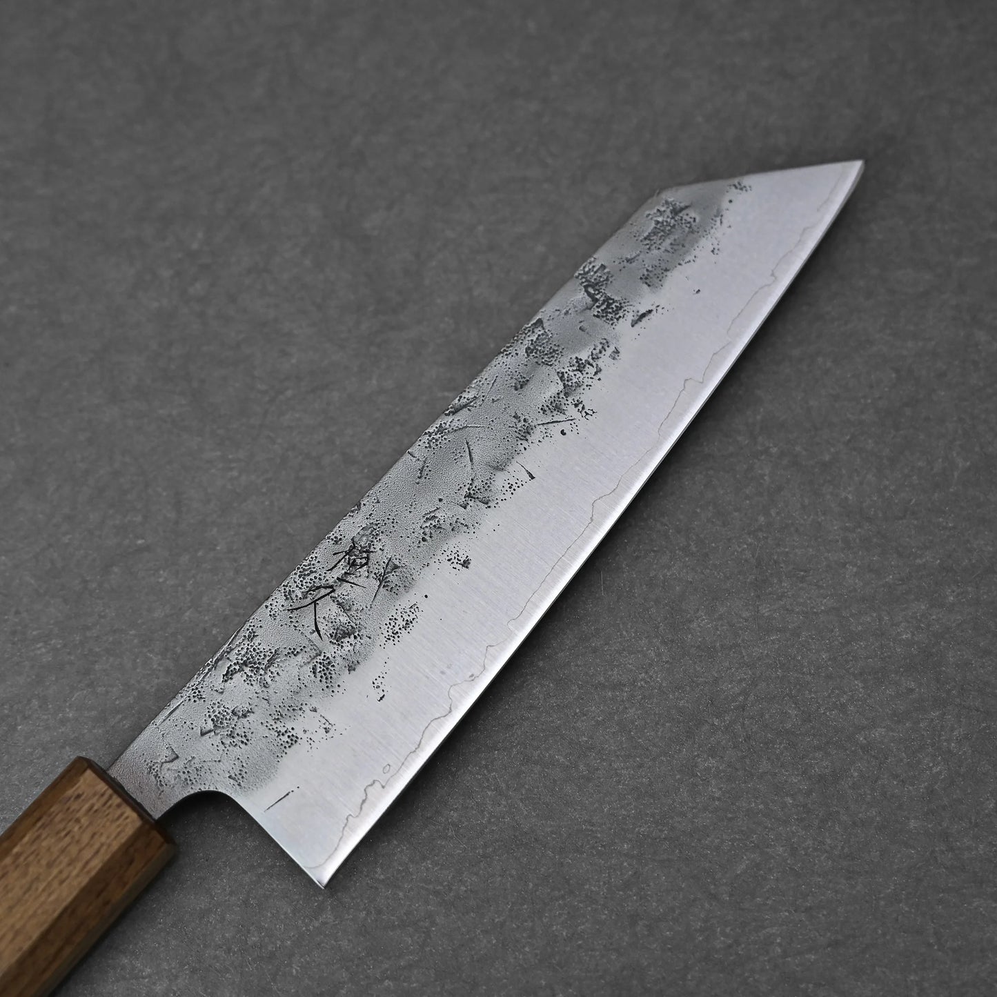The Tsunehisa nashiji SLD bunka 170mm, with a rectangular wooden handle and a wide, pointed SLD steel blade showcasing a textured nashiji finish, is displayed on a gray background.