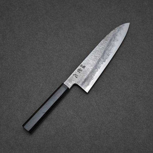 The Yoshihide Masuda aogami#1 damascus santoku 180mm features a Japanese-style damascus blade made from Aogami#1 carbon steel and a black octagonal handle, shown on a dark gray textured surface.