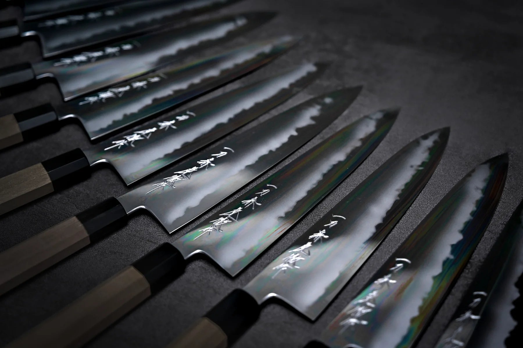 Set of Japanese gyuto knives with reflective blades on a dark background