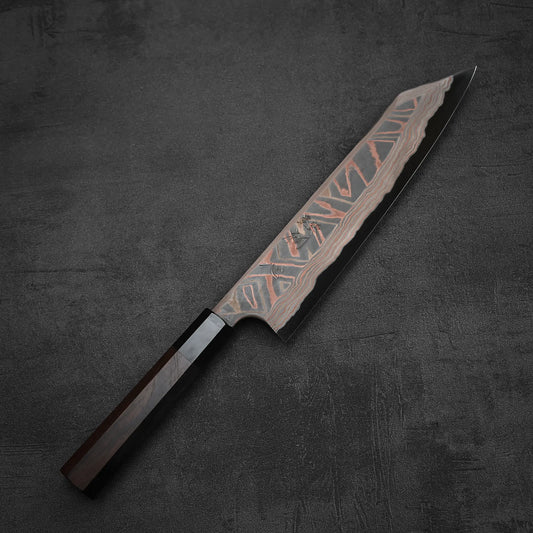 The Hatsukokoro x Nigara Irodori aogami#2 Damascus kiritsuke gyuto 240mm, featuring a striking patterned blade and dark wooden handle, is displayed on a dark textured surface.