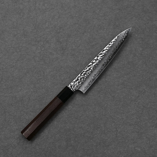 A Hatsukokoro Hayabusa tsuchime VG10 petty knife 150mm with a hammered, patterned blade and dark wooden handle rests on a gray surface, highlighting the craftsmanship of Seki Japan.