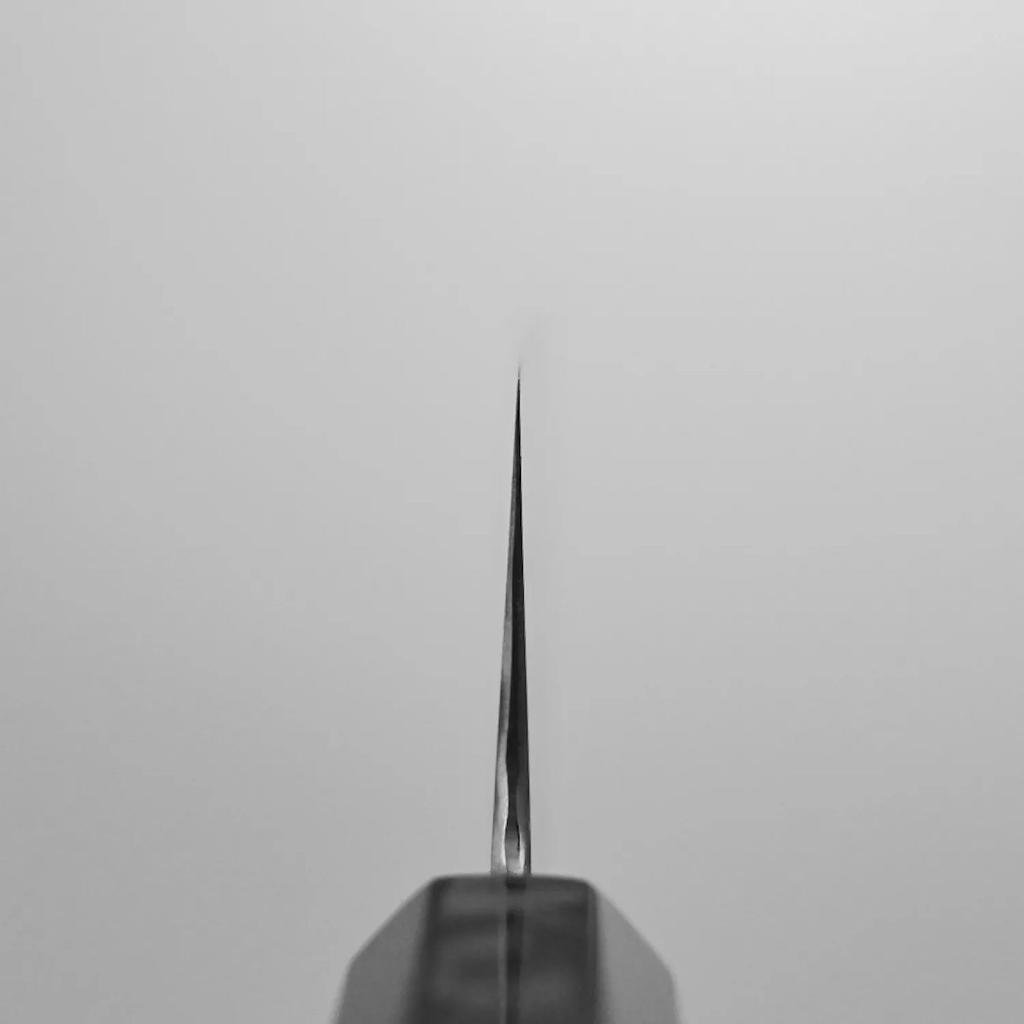 Choil shot of the Ittosai Kotetsu damascus aogami#1 gyuto 240mm, photographed from the tip looking straight down the spine against a neutral gray background.