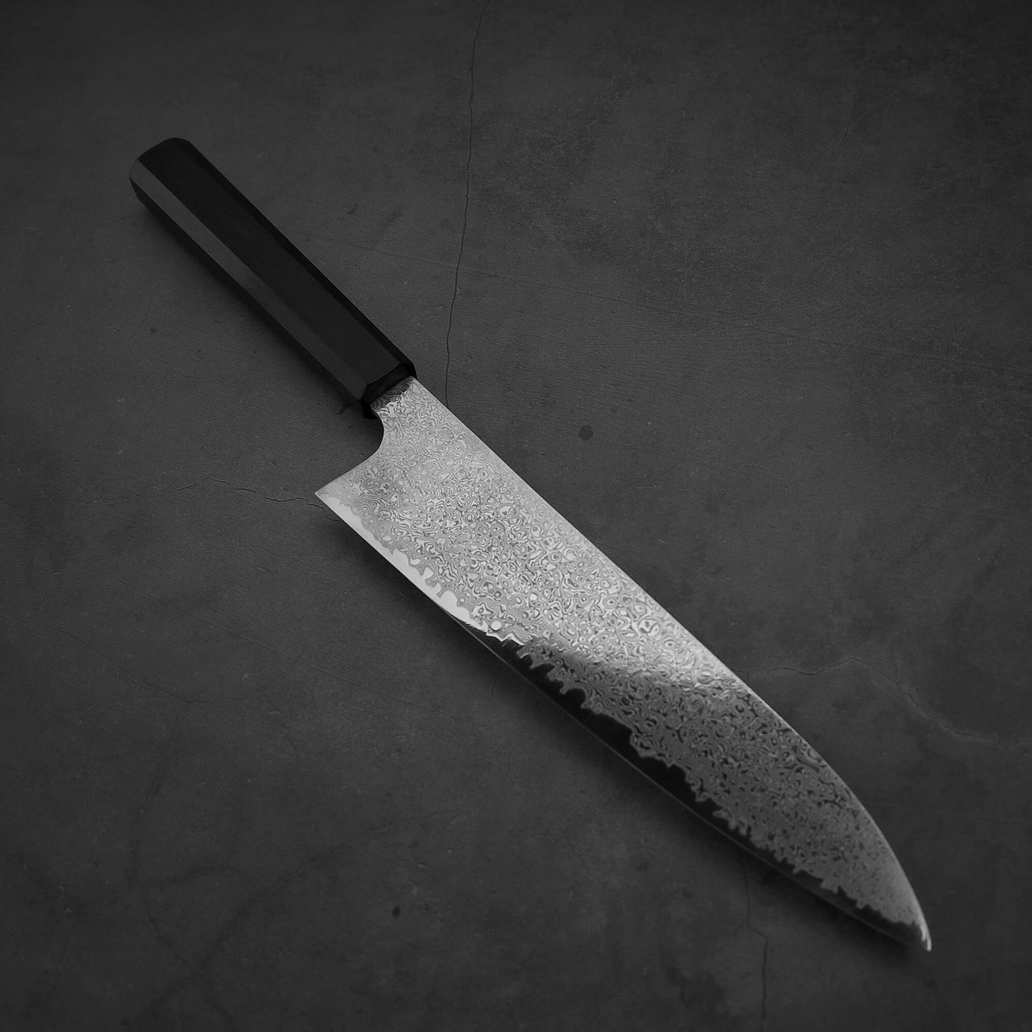 Top view of Hatsukokoro ginsan damascus gyuto 210mm. Tip is facing the bottom right.
