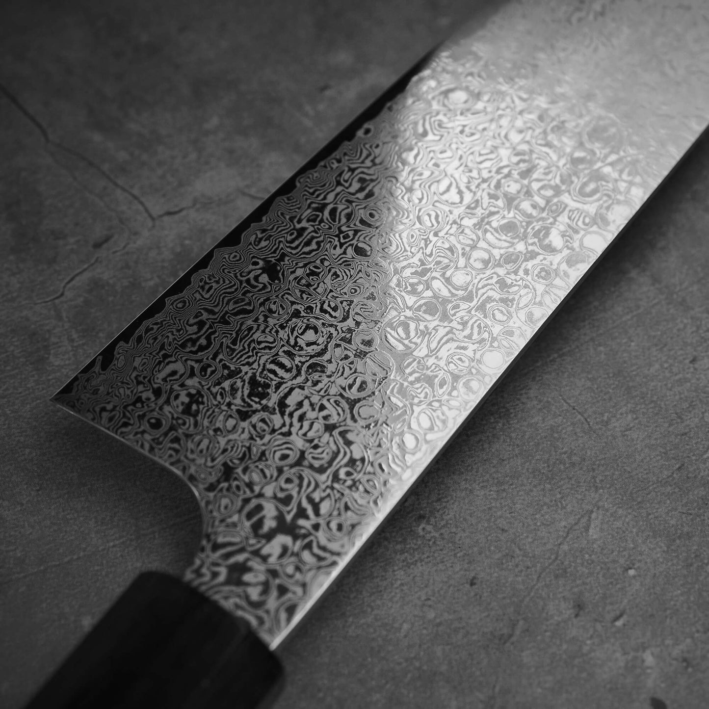 Close up view of Hatsukokoro ginsan damascus gyuto 240mm. Image focuses on the left side of the blade.