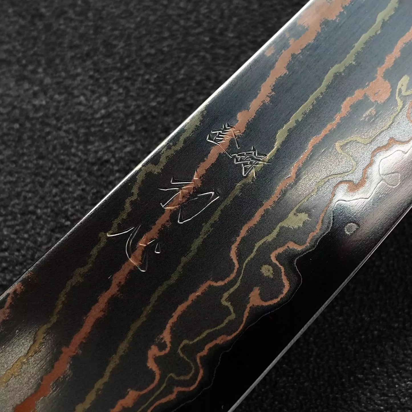 Close up view of the kanji of Hatsukokoro Habayusa aogami#2 rainbow damascus petty knife