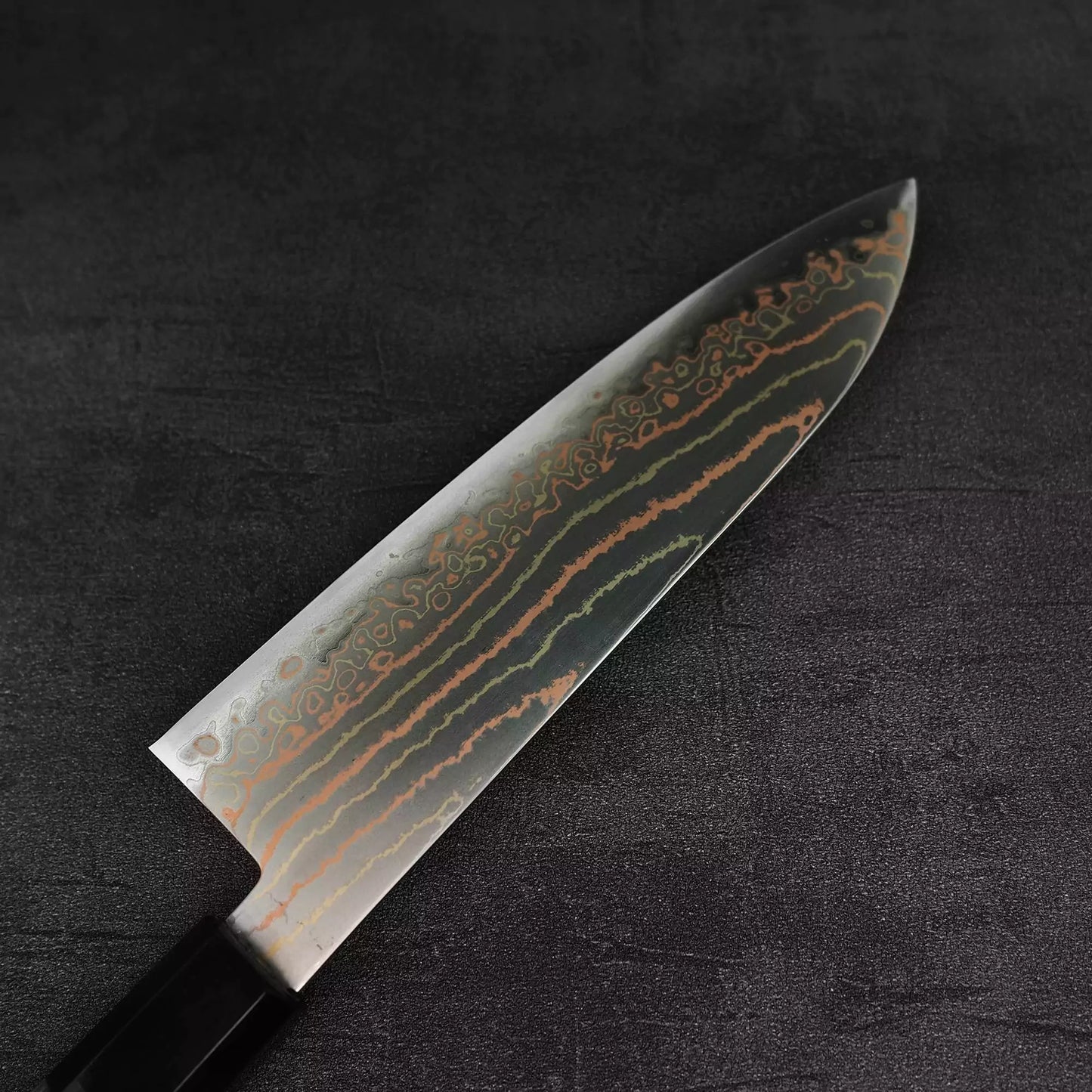 Close up view of the back side of Hatsukokoro Habayusa aogami#2 rainbow damascus santoku knife