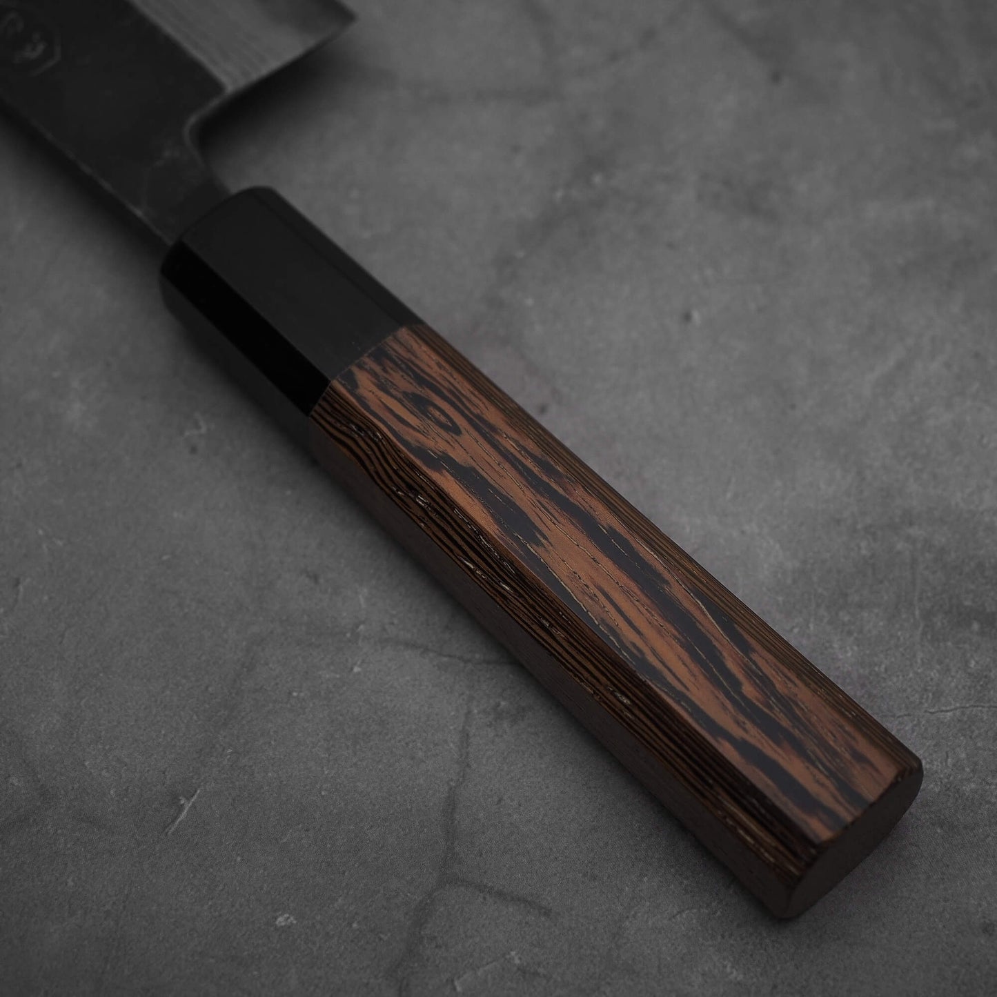 Close up view of the wenge handle of Hatsukokoro Kumokage kurouchi damascus aogami#2 nakiri knife