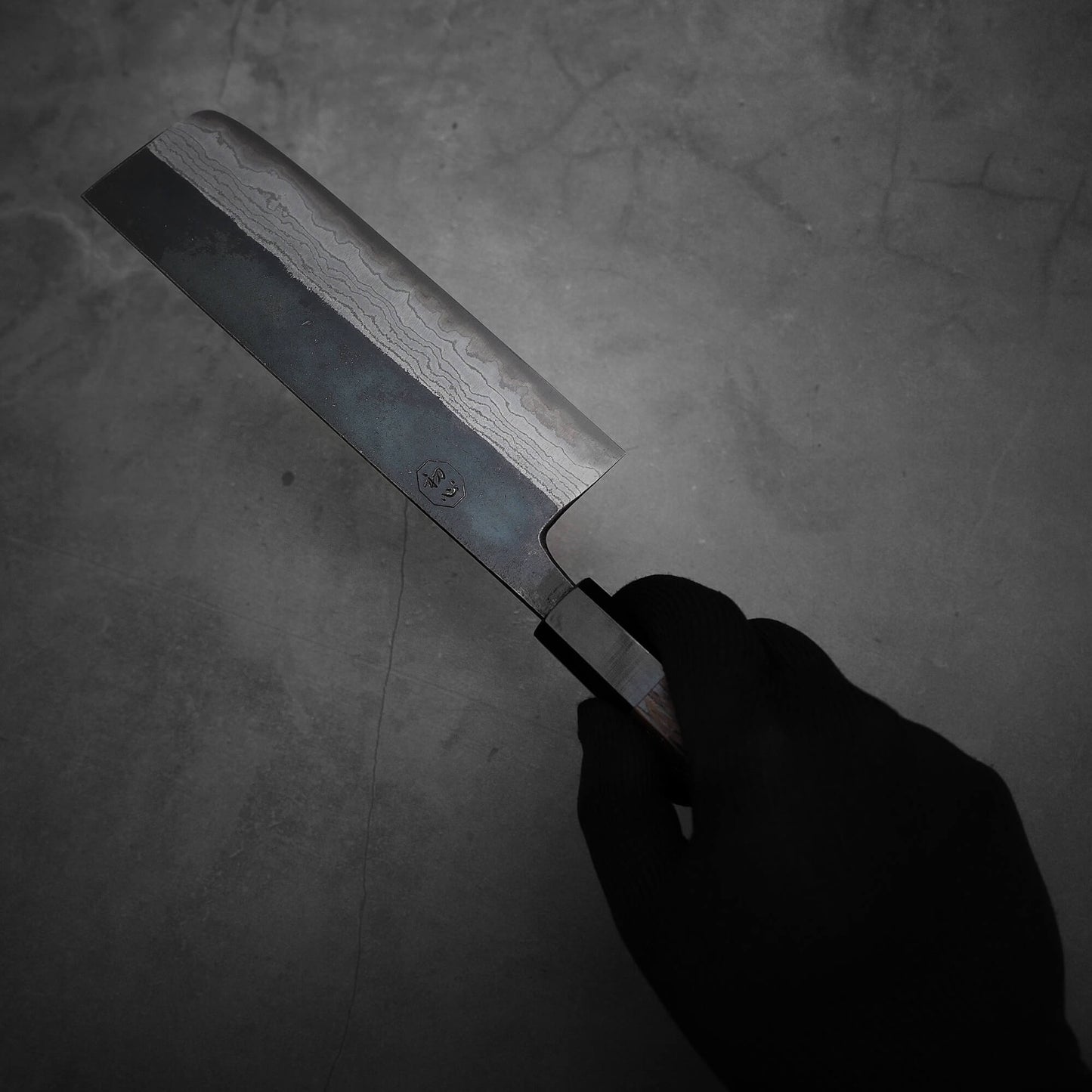 Hand holding Hatsukokoro Kumokage kurouchi damascus aogami#2 nakiri knife