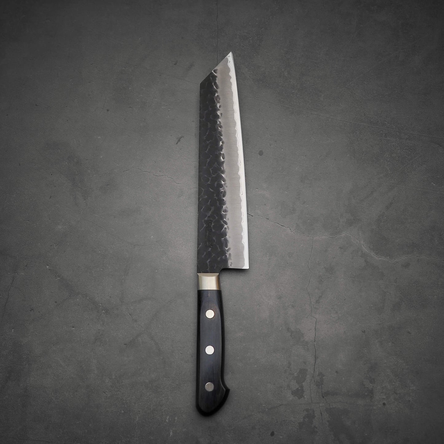 Top view of Ittosai Kotetsu tsuchime kurouchi aogami super kiritsuke gyuto in vertical position