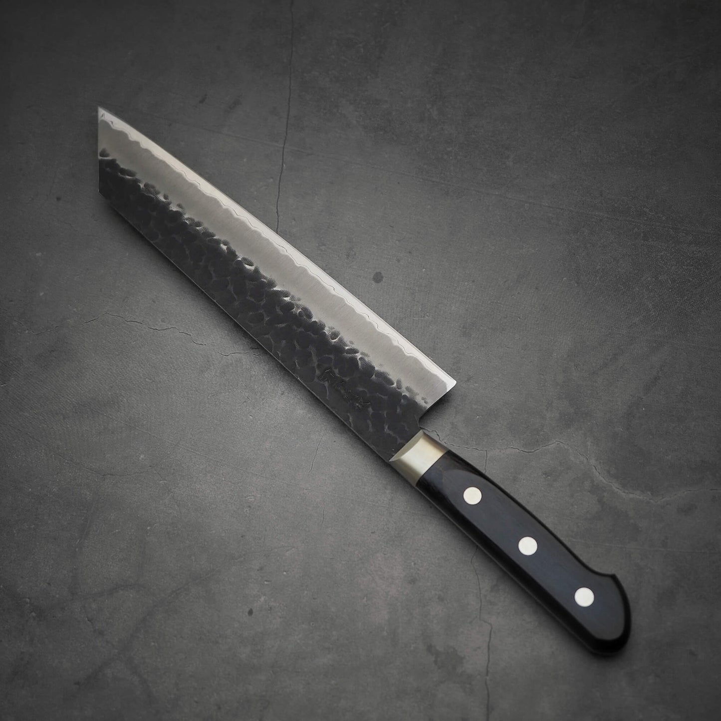 Top view of Ittosai Kotetsu tsuchime kurouchi aogami super kiritsuke gyuto where tip is facing upper left