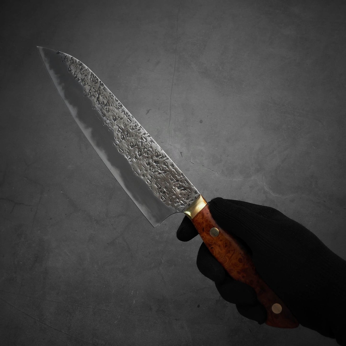 Another photo showing a hand holding a 220mm Kisuke Manaka tsuchime honwarikomi shirogami#2 gyuto knife. The pointed tip is facing towards the upper left.