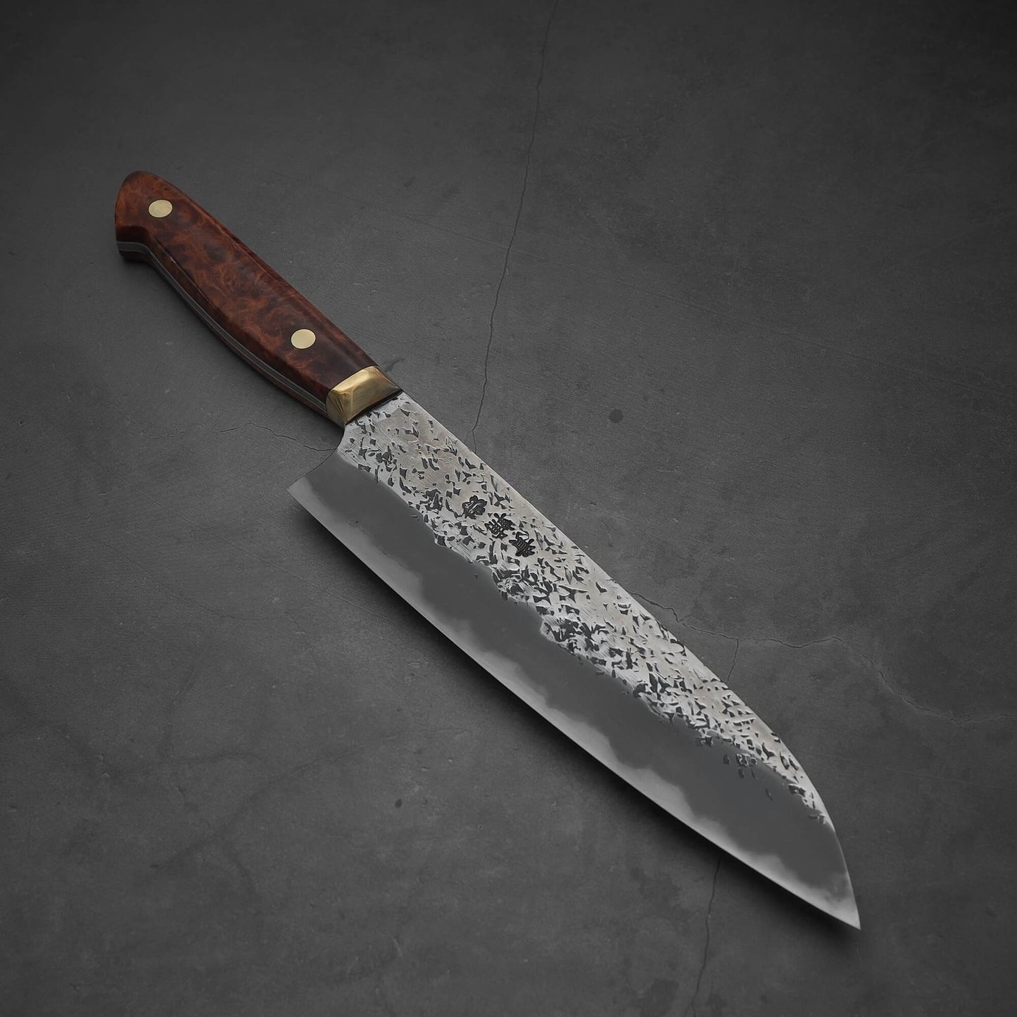 Top view of a 220mm Kisuke Manaka tsuchime honwarikomi shirogami#2 gyuto knife where the tip faces the lower right