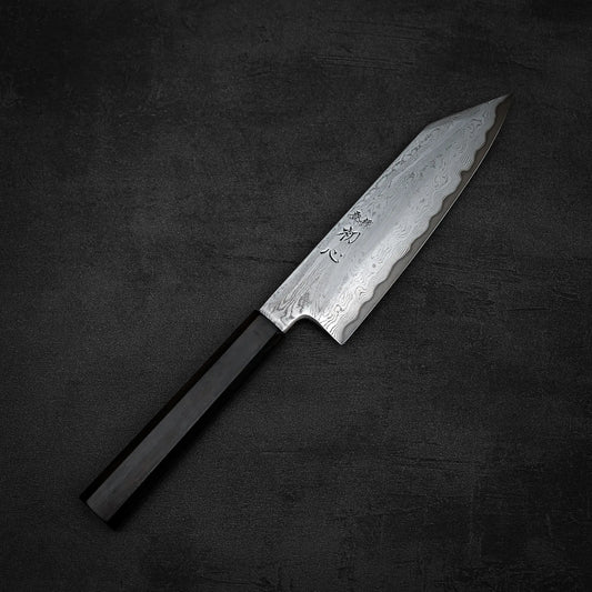 The Satoshi Nakagawa Nakagawa aogami#1 damascus bunka 180mm - etched, featuring a dark wooden handle and patterned steel blade, rests on a textured dark grey surface, showcasing Japanese carbon steel craftsmanship.