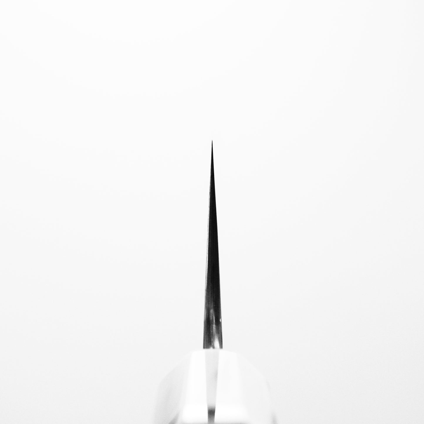 Close-up of the Nigara Hamono Nigara aogami#2 + shirogami#2 coreless honyaki gyuto 300mm’s pointed tip, blade vertical against a white background—showcasing refined Japanese swordsmith artistry.