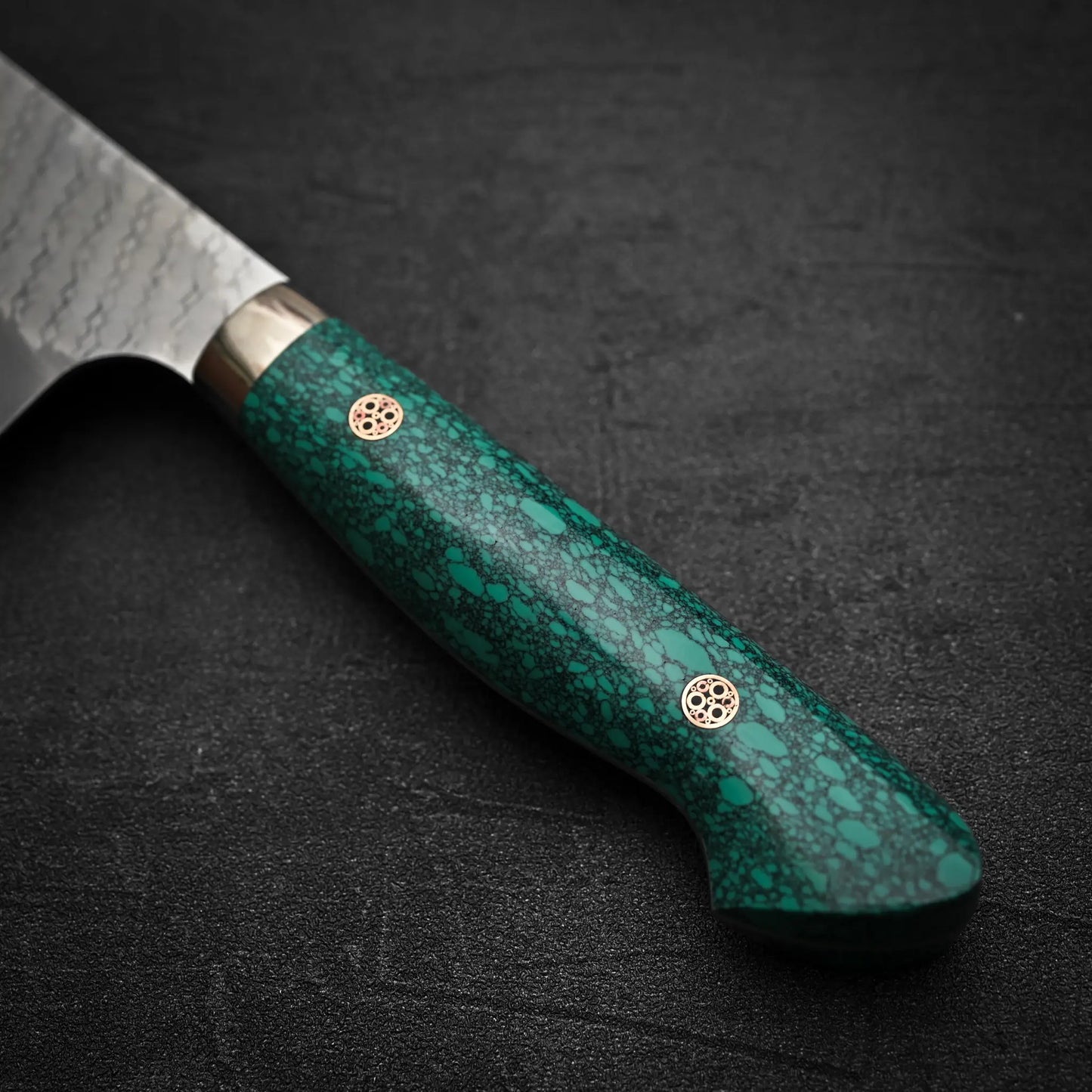 A close-up of the Nigara Hamono Nigara tsuchime SG2 kiritsuke nakiri 180mm, showing its green speckled handle with two decorative rivets, ideal for prepping vegetables on a dark textured backdrop.