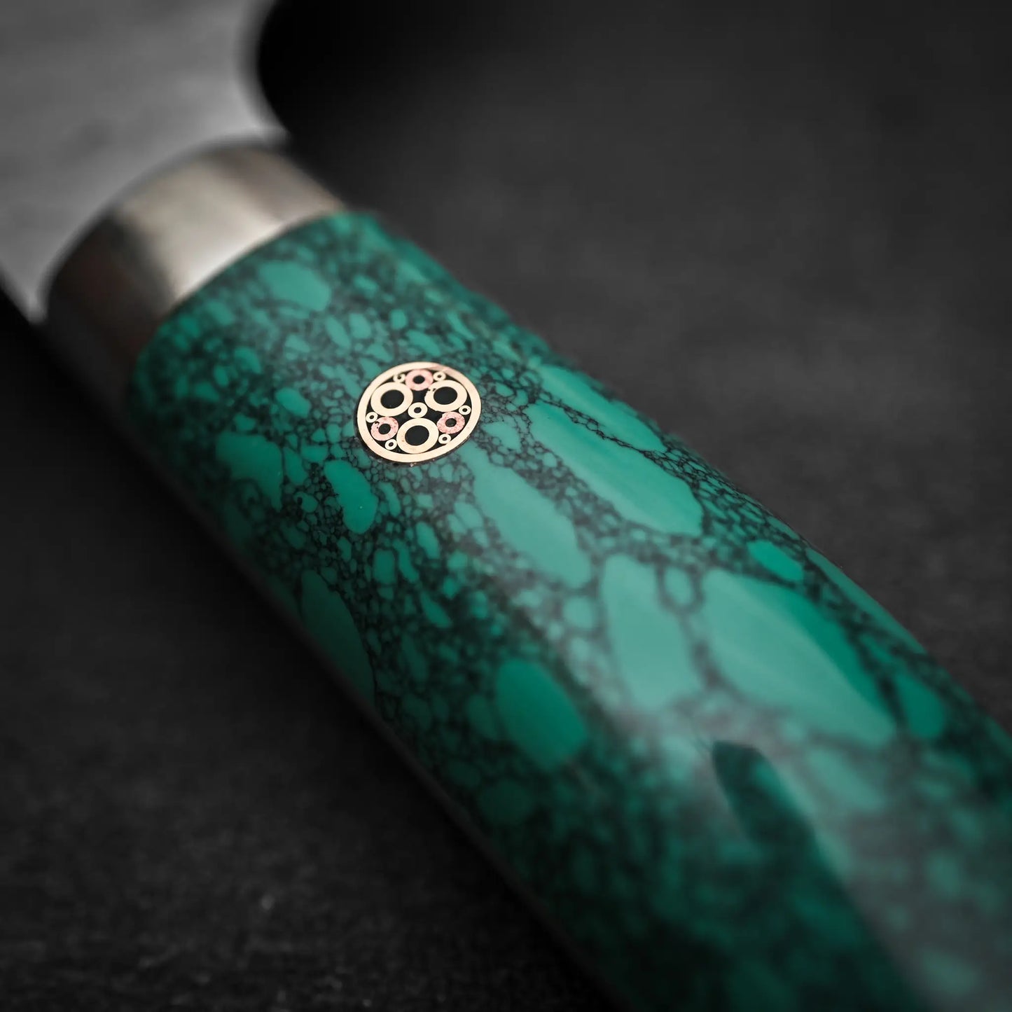 Close-up of the Nigara Hamono Nigara tsuchime SG2 kiritsuke nakiri 180mm knife handle, featuring a green marbled pattern and decorative circular pin—ideal for vegetable prep, set against a plain dark background.