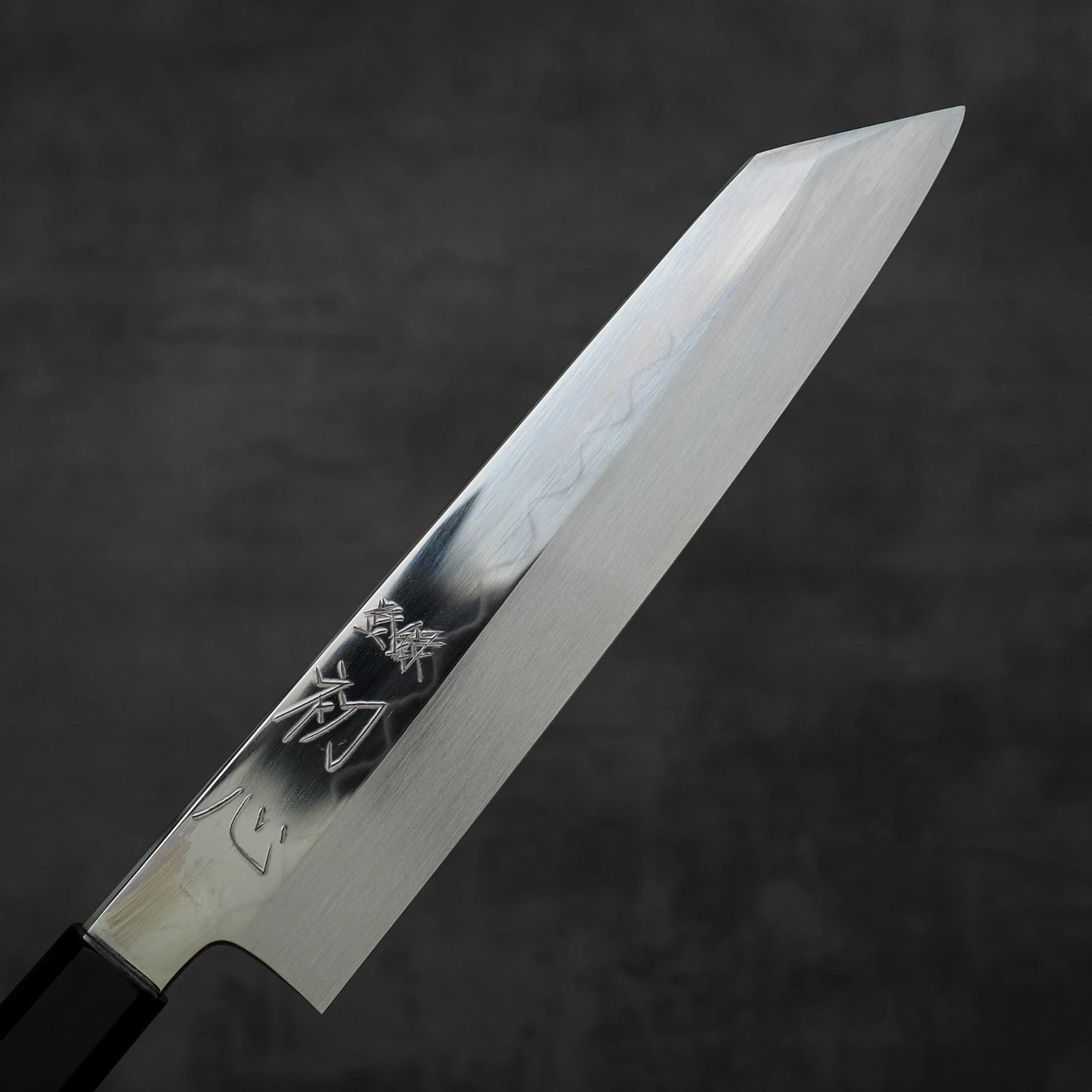 A close-up of the Satoshi Nakagawa Nakagawa shirogami#3 honyaki kiritsuke gyuto 210mm, featuring a polished, kanji-engraved blade, crafted in Japanese tradition and set against a plain dark background.