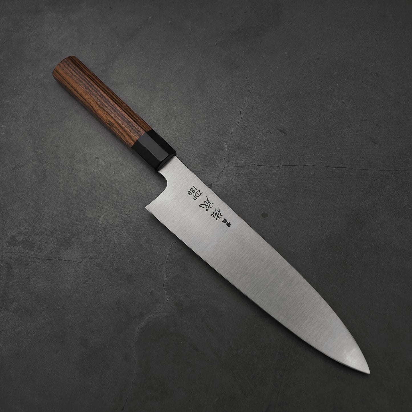 Top view of a 240mm Sukenari ZDP189 gyuto knife where the pointed tip is facing towards the lower right