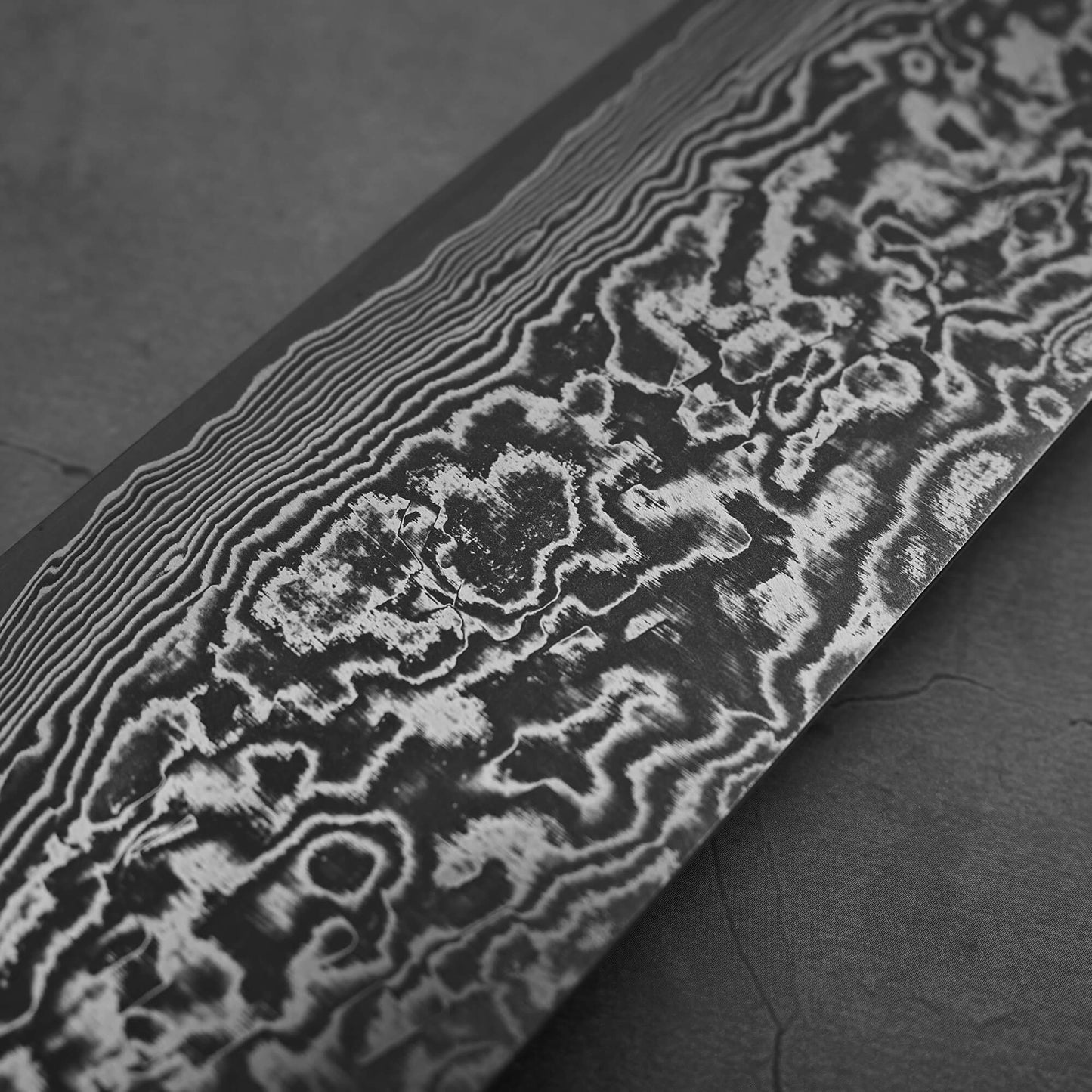 Another close up view of Takeshi Saji black damascus SG2 nakiri ironwood. Image focuses on the left side of the blade