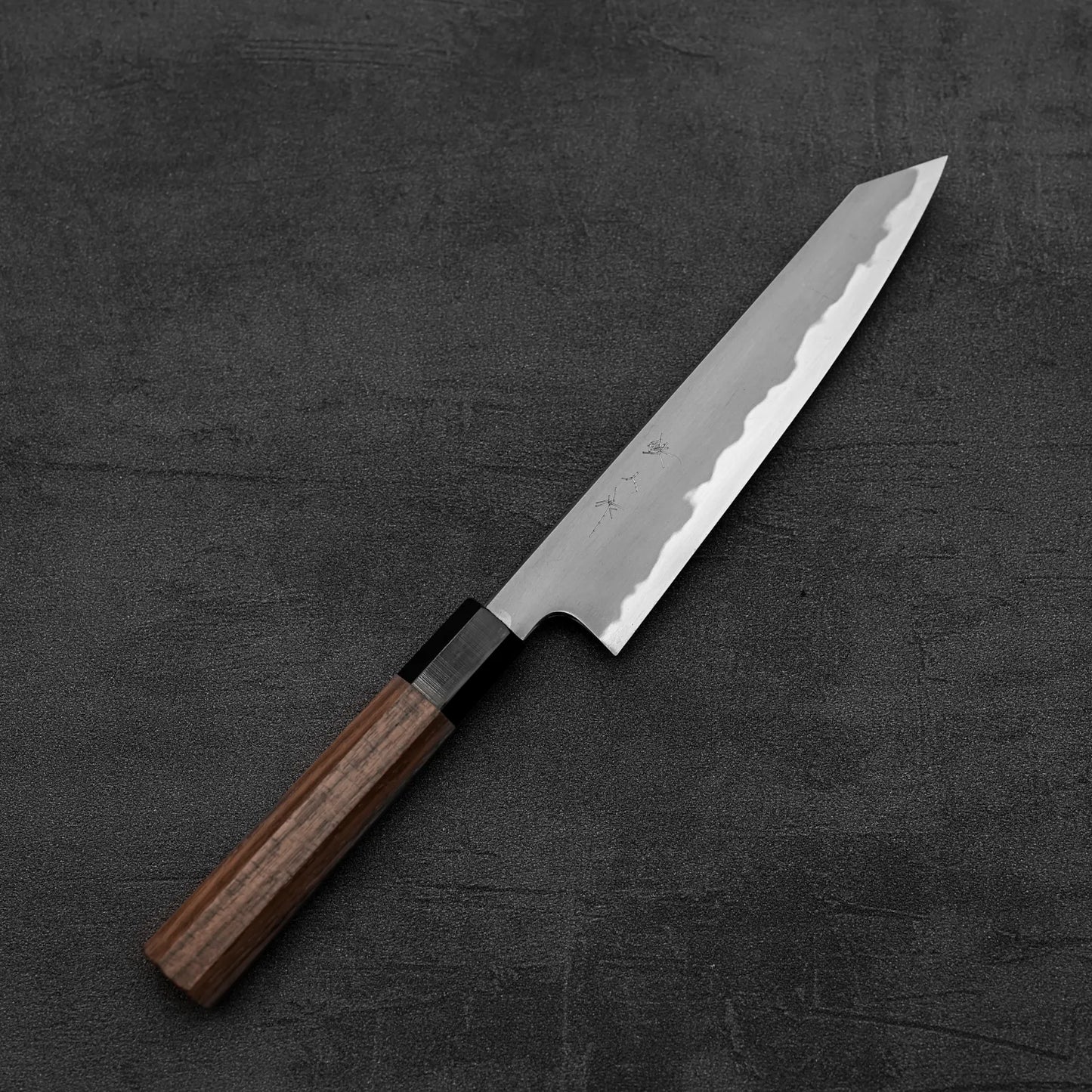 The Tetsujin kasumi aogami#2 petty knife 165mm, featuring a wooden handle and sharp stainless steel blade with kasumi finish, is displayed on a dark, textured surface.
