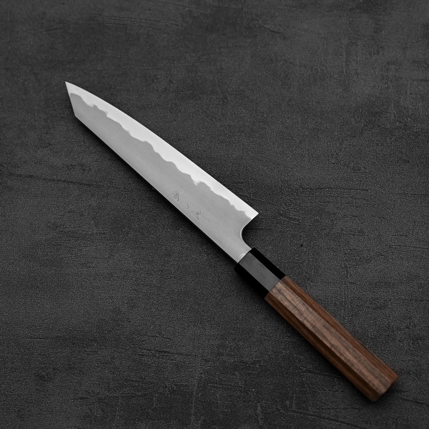 The Tetsujin kasumi aogami#2 petty knife 165mm by Tetsujin features a premium patterned blade and dark wooden handle, shown resting on a textured dark gray surface.