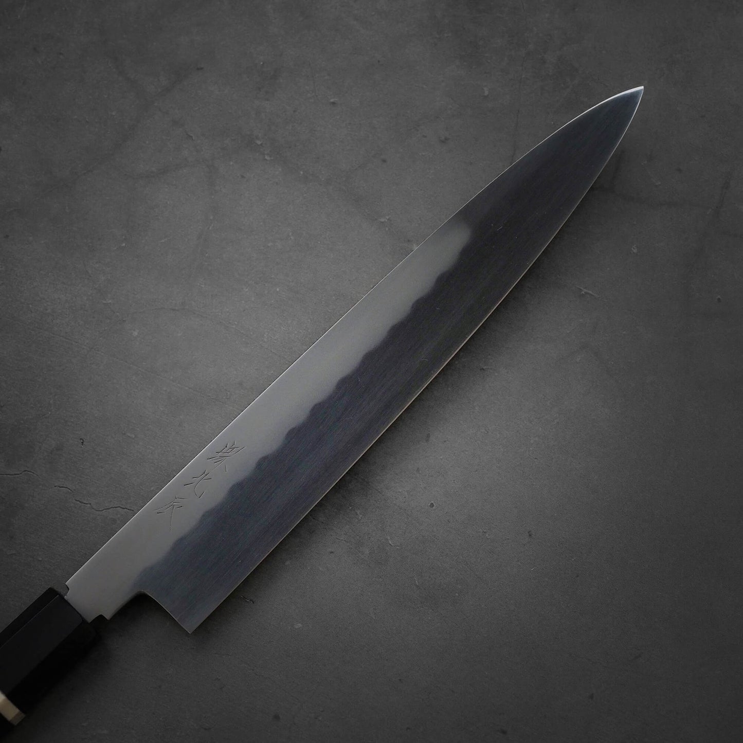 Close up view of the blade of Yoshikazu Ikeda honyaki sujihiki. This hand-forged Japanese knife is made of shirogami#3 steel.