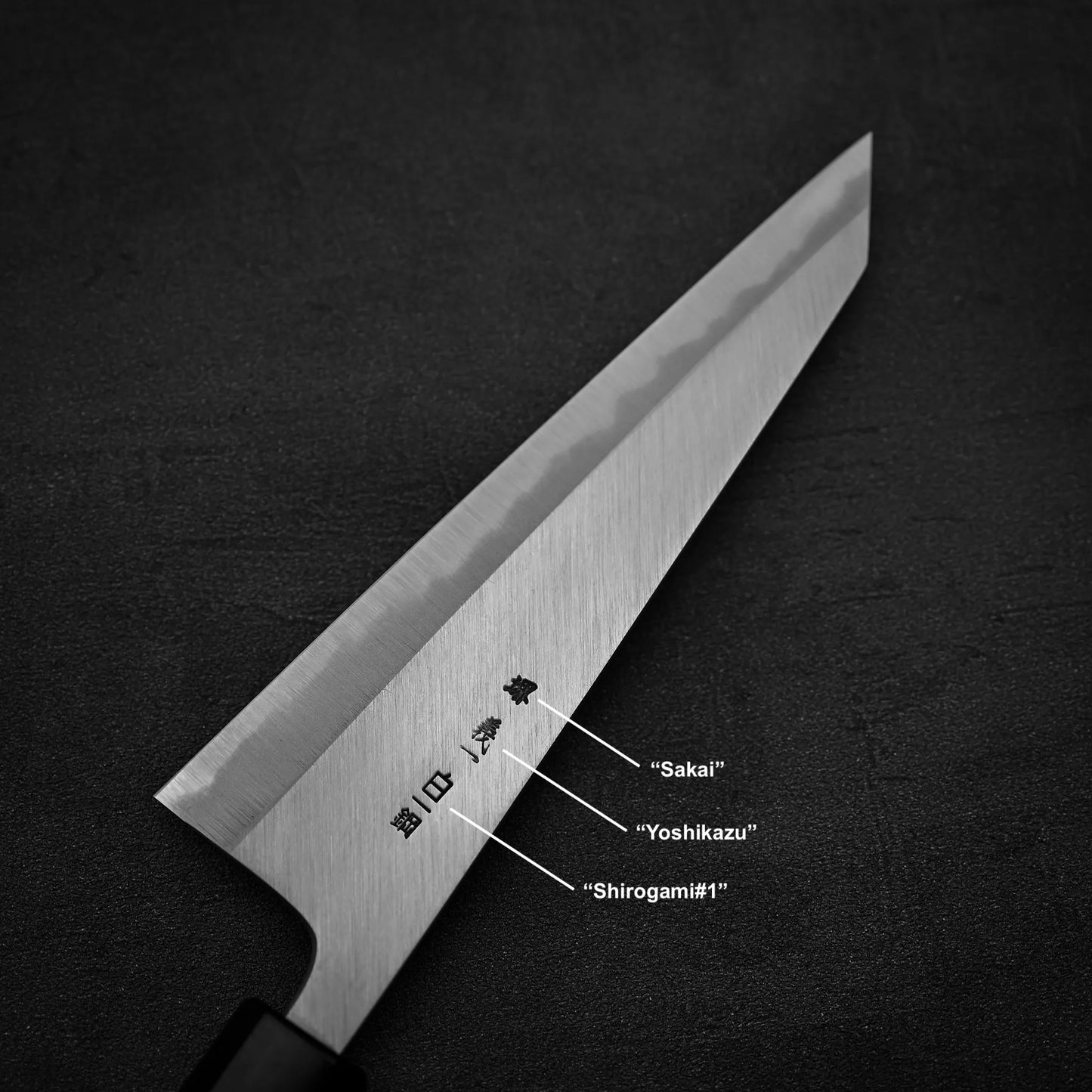 A close-up of the Yoshikazu Tanaka shirogami#1 double bevel honesuki 170x50 shows engraved kanji on the blade, with Sakai, Yoshikazu Tanaka, and shirogami#1 steel labels highlighting fine Japanese craftsmanship.