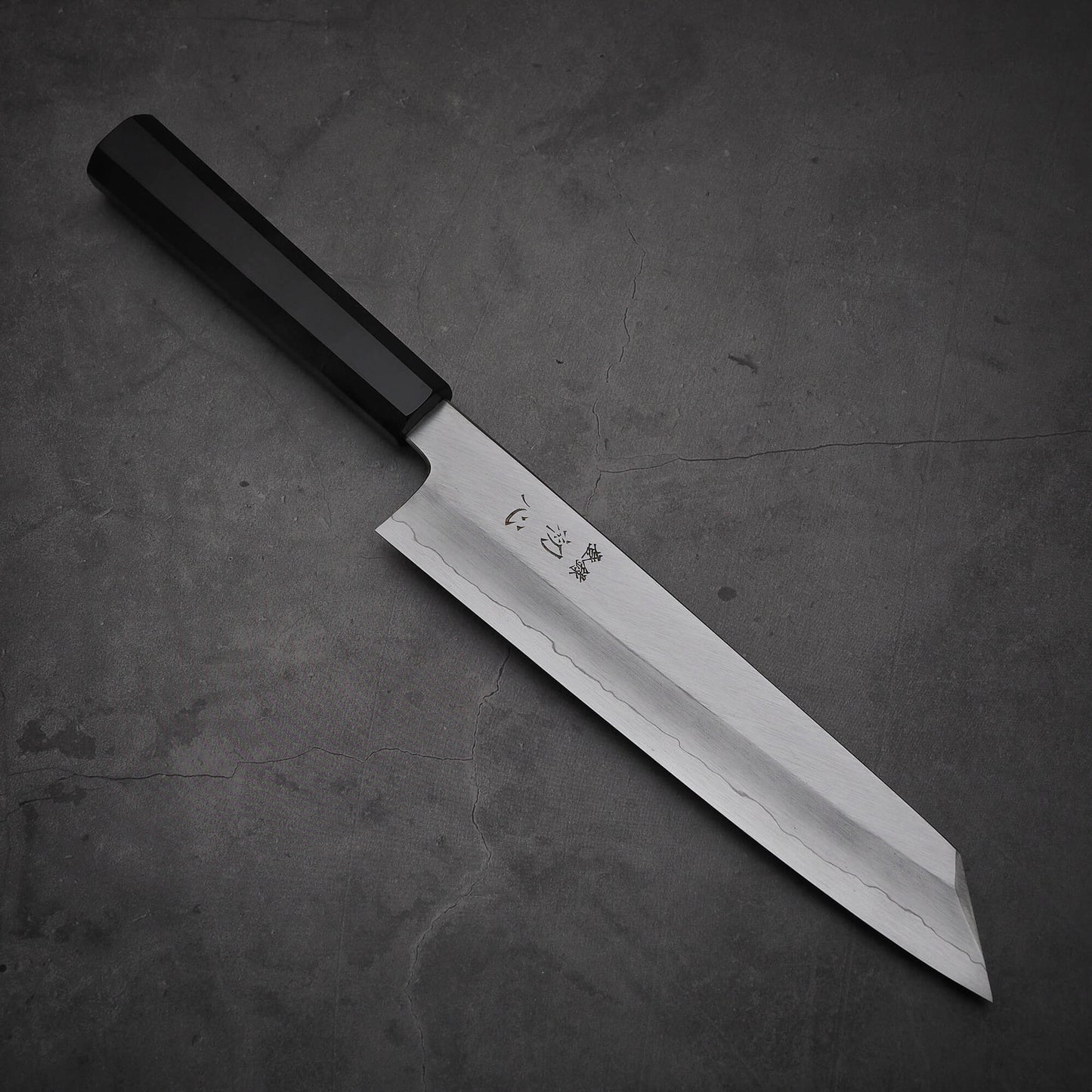 Top view of Hatsukokoro Nakagawa ginsan kiritsuke gyuto knife where pointed tip is facing towards lower right