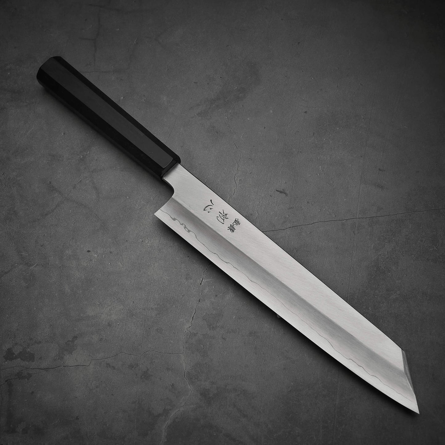 Top view of Hatsukokoro Nakagawa ginsan kiritsuke gyuto knife where pointed tip is facing towards lower right