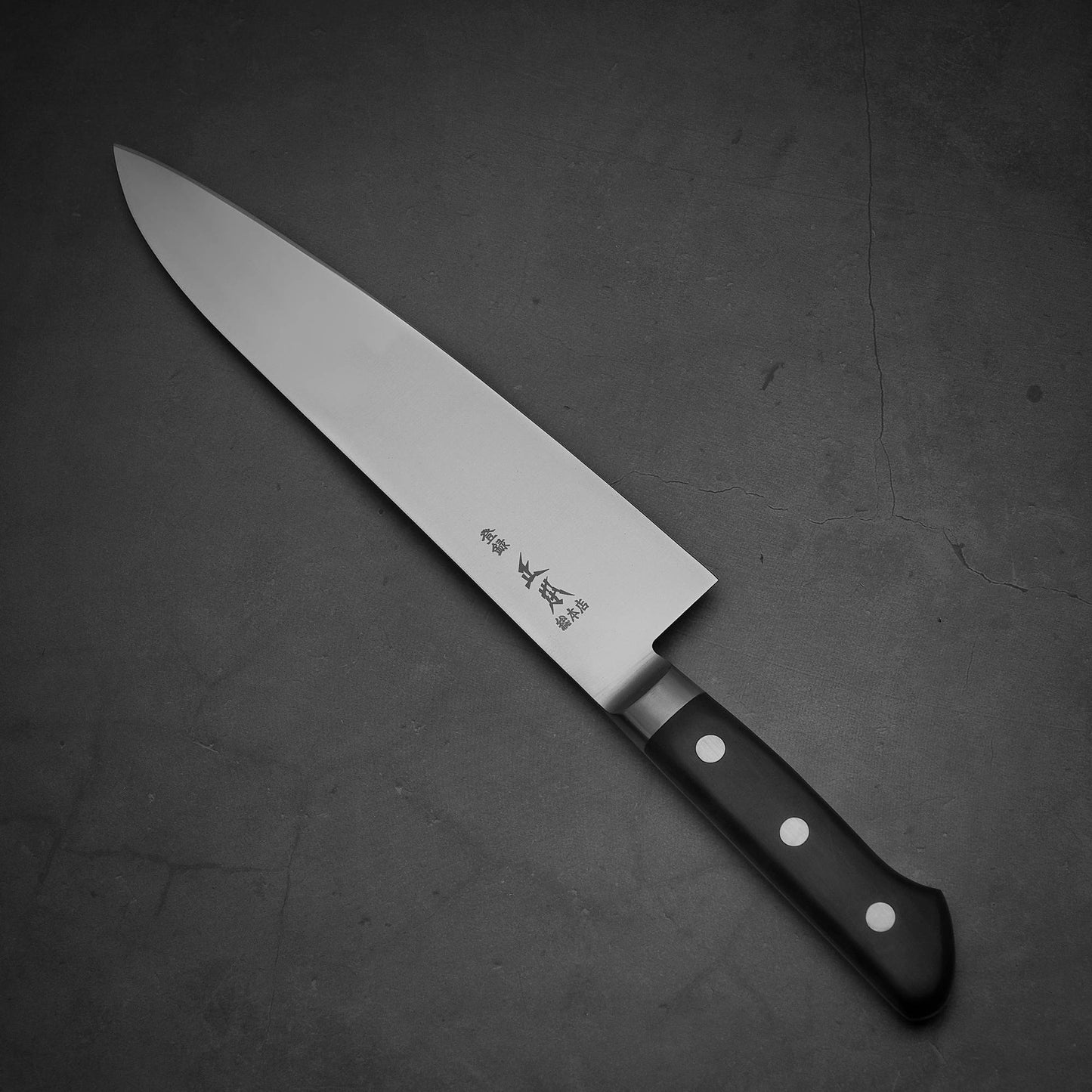 Top view of Masamoto VG yo-gyuto knife where pointed tip is facing towards upper left