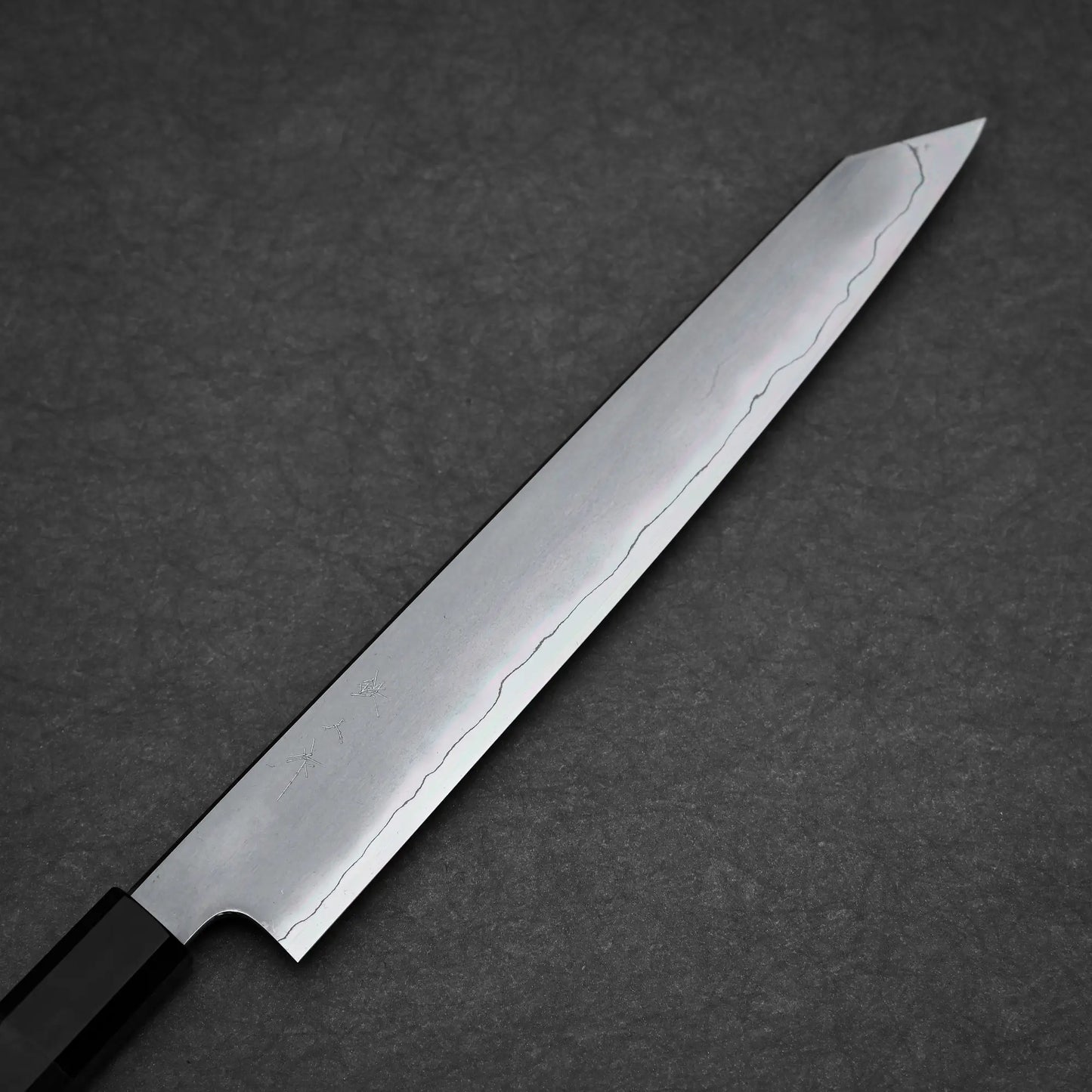 The Tetsujin kasumi ginsan kiritsuke sujihiki 240mm is a single-edged Japanese knife with a long, narrow Ginsan steel blade, kasumi finish, and wavy line pattern near the edge, shown against a dark textured background.