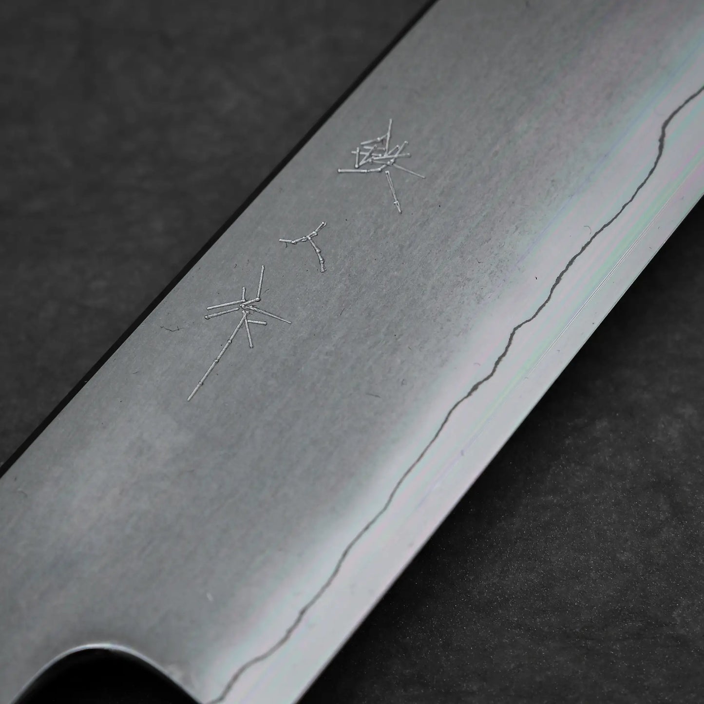 Close-up of the Tetsujin kasumi ginsan kiritsuke sujihiki 240mm blade by Tetsujin, featuring Ginsan steel, engraved kanji, and a wavy kasumi finish along the edge, set against a dark background.