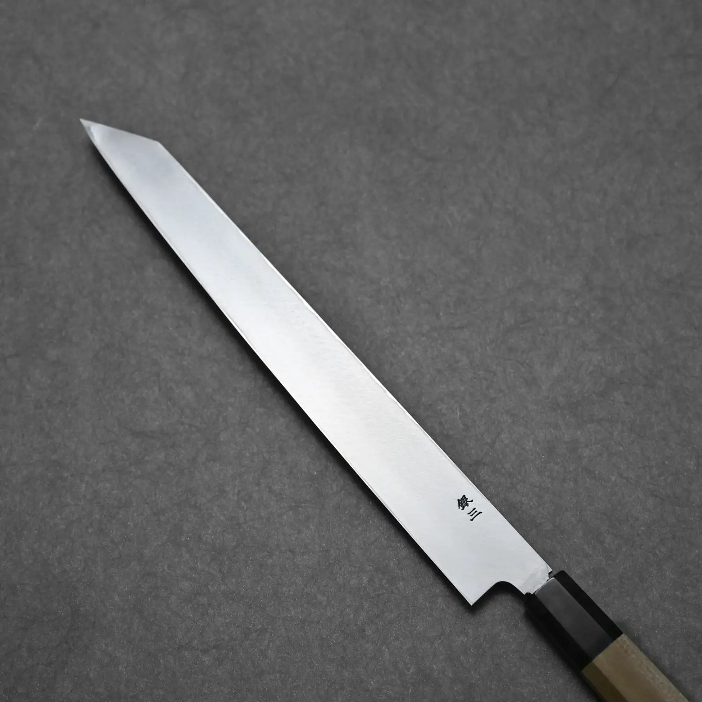Angled view of the back side of 270mm ktip yanagi showing the urasuki and ginsan steel stamp