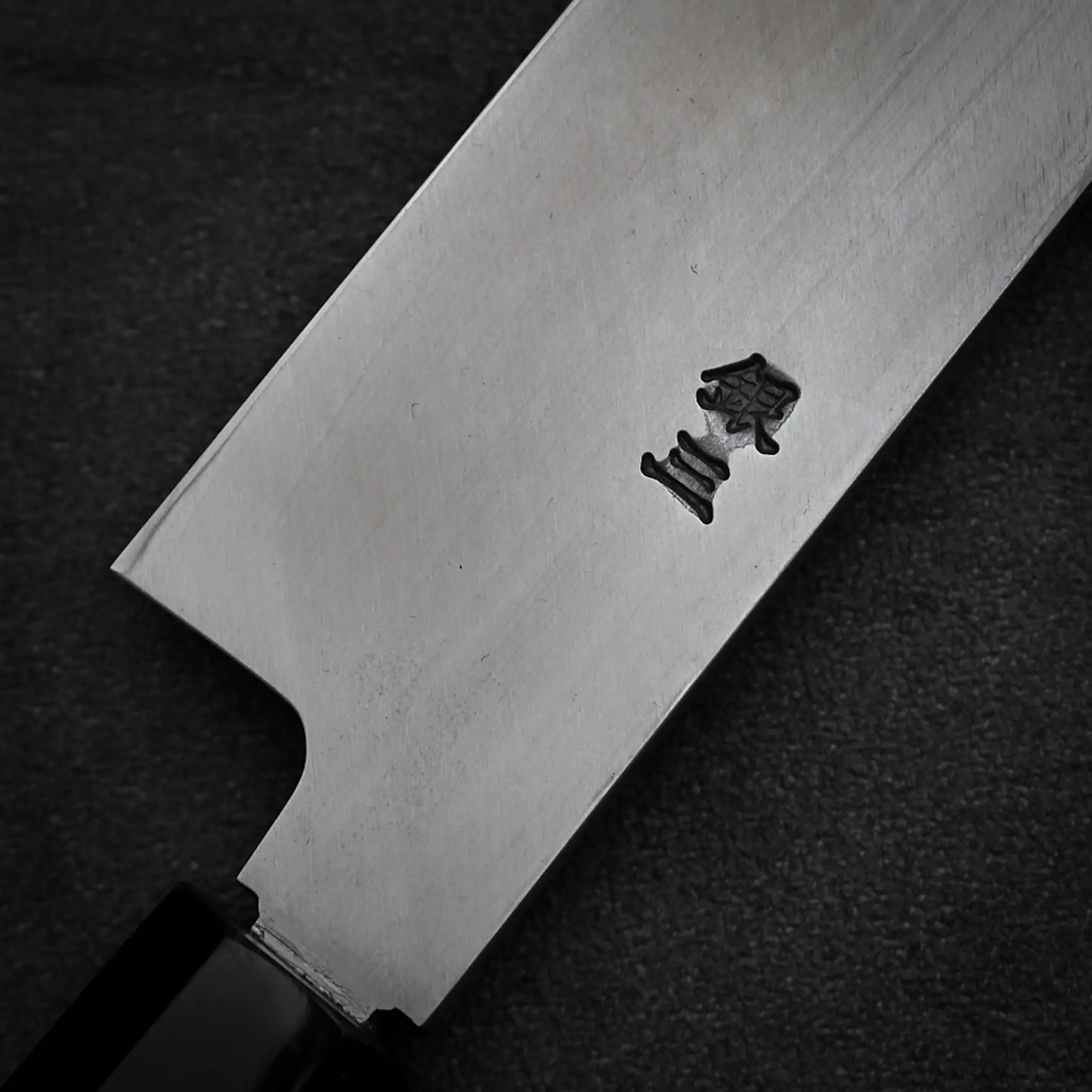 A close-up of the Tsunehisa ginsan yanagiba 270mm blade with two kanji engravings, set against a dark background. The Ginsan stainless steel handle from Tsunehisa is partially visible in the lower left corner.