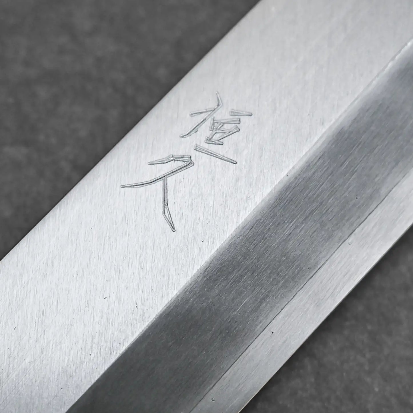 Detailed view of the kanji stamp on the front blade of the ginsan yanagi