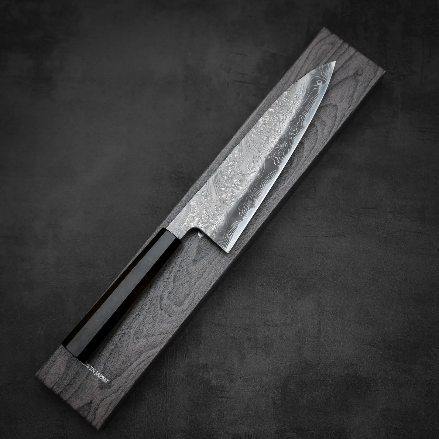 Top down view of Yoshihide Masuda shirogami#2 damascus tall gyuto knife with its box