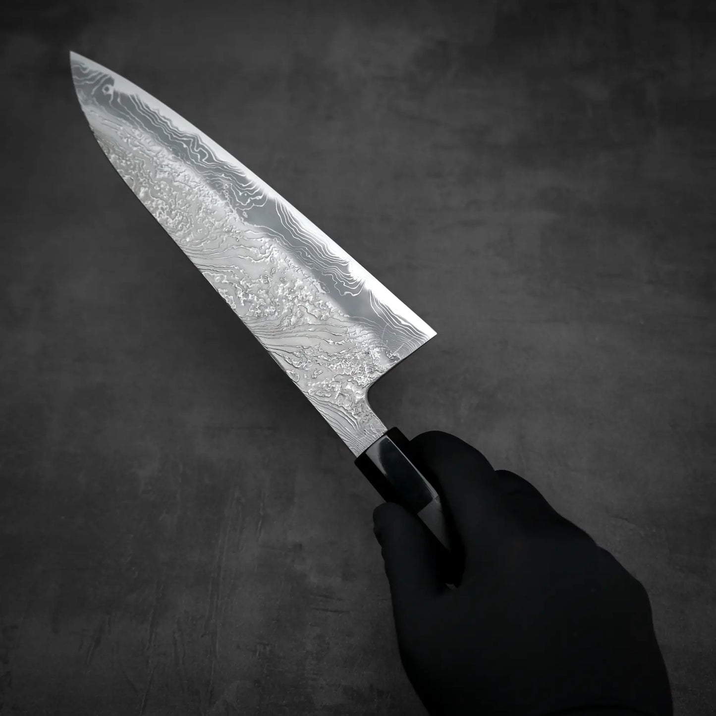 Top down view of Yoshihide Masuda shirogami#2 damascus tall gyuto knife being held in hand