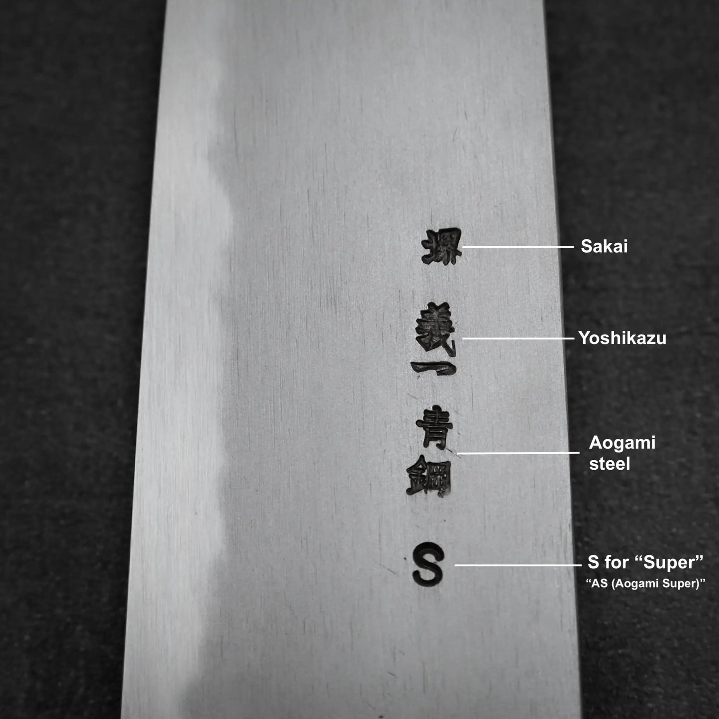 Close-up of the Yoshikazu Tanaka AS tall gyuto 210mm blade, showing Japanese kanji and English markings for Yoshikazu Tanaka, Aogami Super steel, and Sakai—emphasizing its premium craftsmanship.