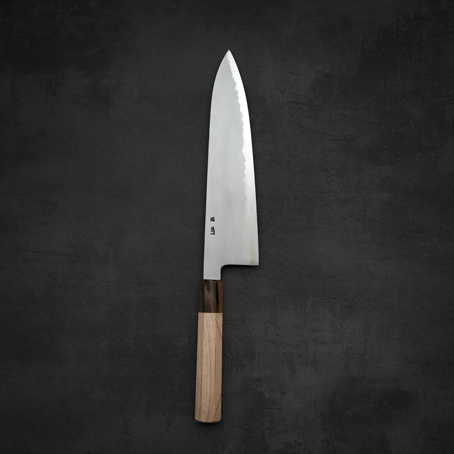 The Yoshikazu Tanaka AS tall gyuto 240mm features a polished, wide stainless steel blade with subtle markings and a wooden handle, reflecting the craftsmanship of Sakai blacksmith Yoshikazu Tanaka.
