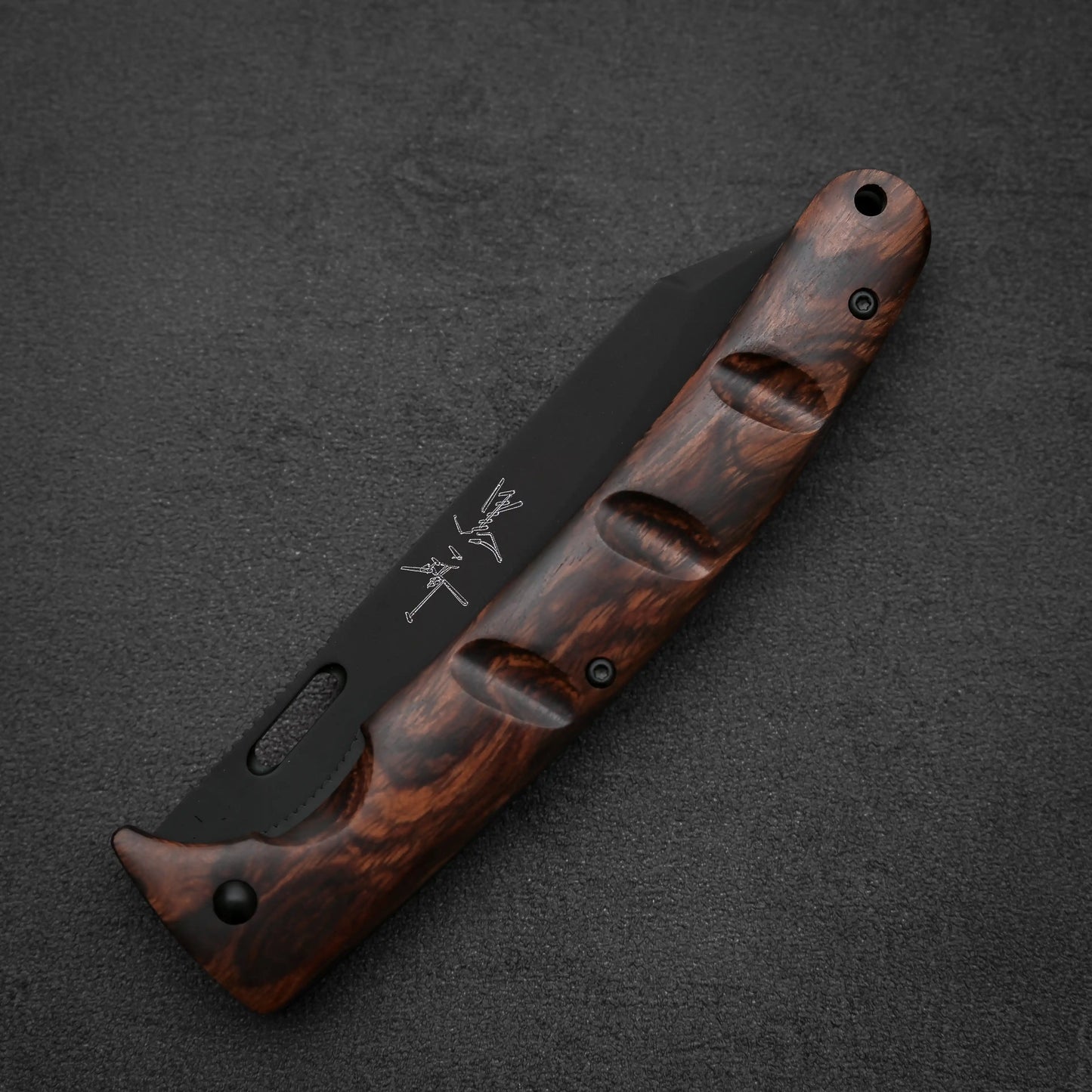 The Yu Kurosaki SG2 folding pocket knife features a dark, textured ironwood handle and a partially visible black SG2 stainless steel blade with white markings, displayed against a dark, textured background.