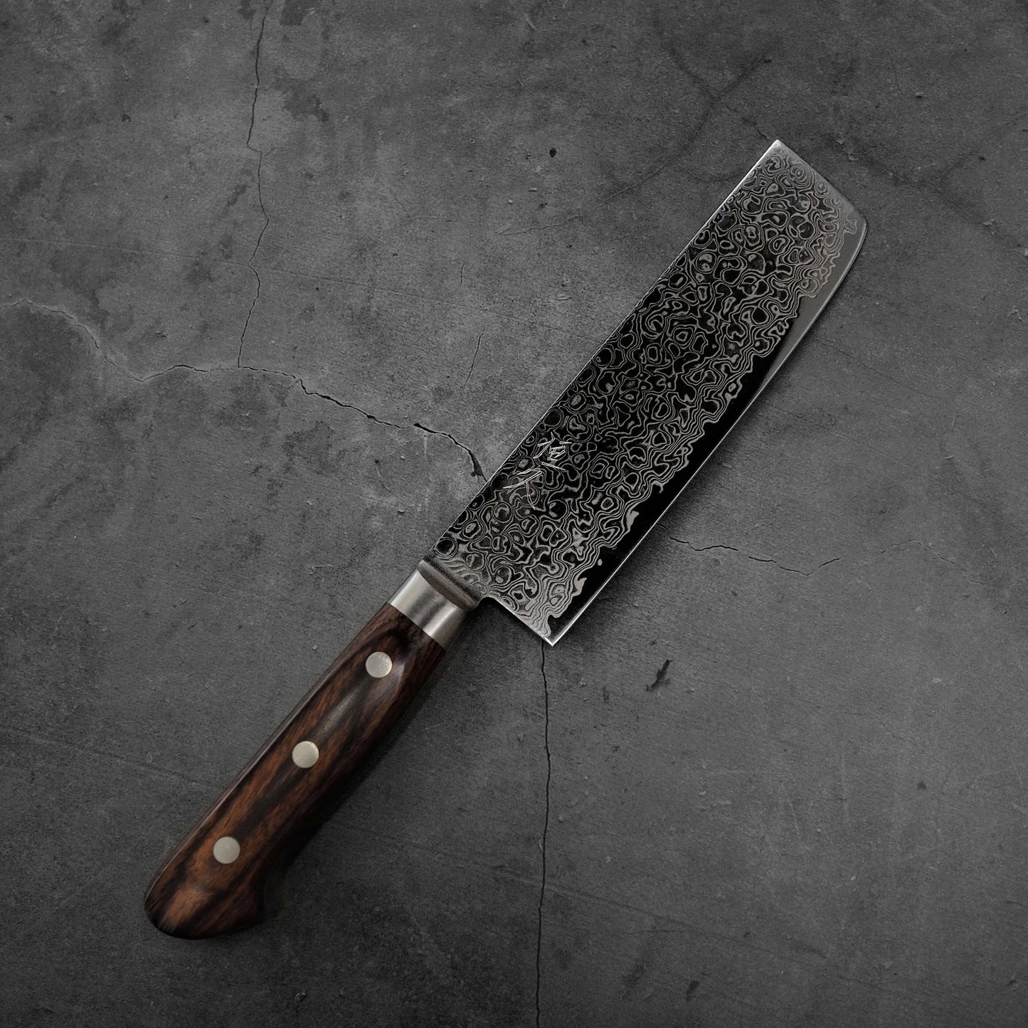 Top view of Tsunehisa ZA18 damascus nakiri knife where tip area is facing upper right