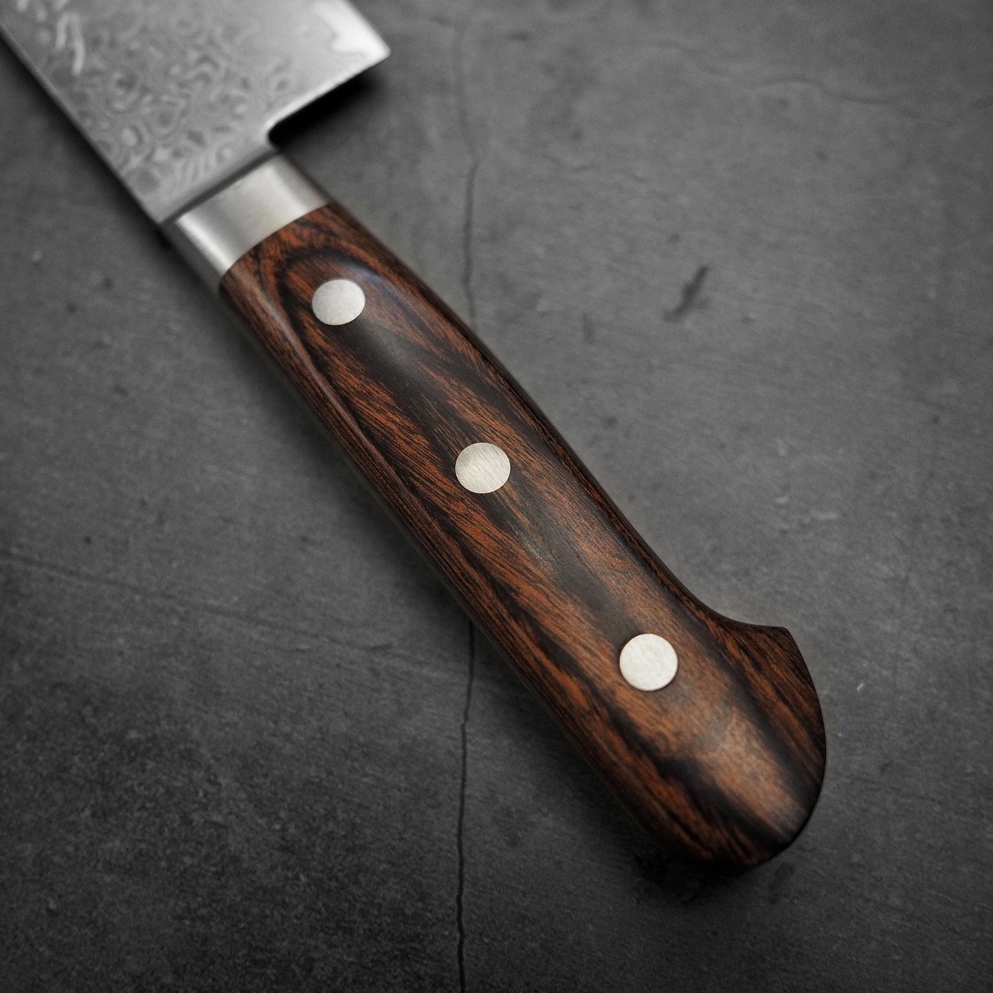 Close up view of Tsunehisa ZA18 damascus nakiri knife. Image focuses on the handle of the knife
