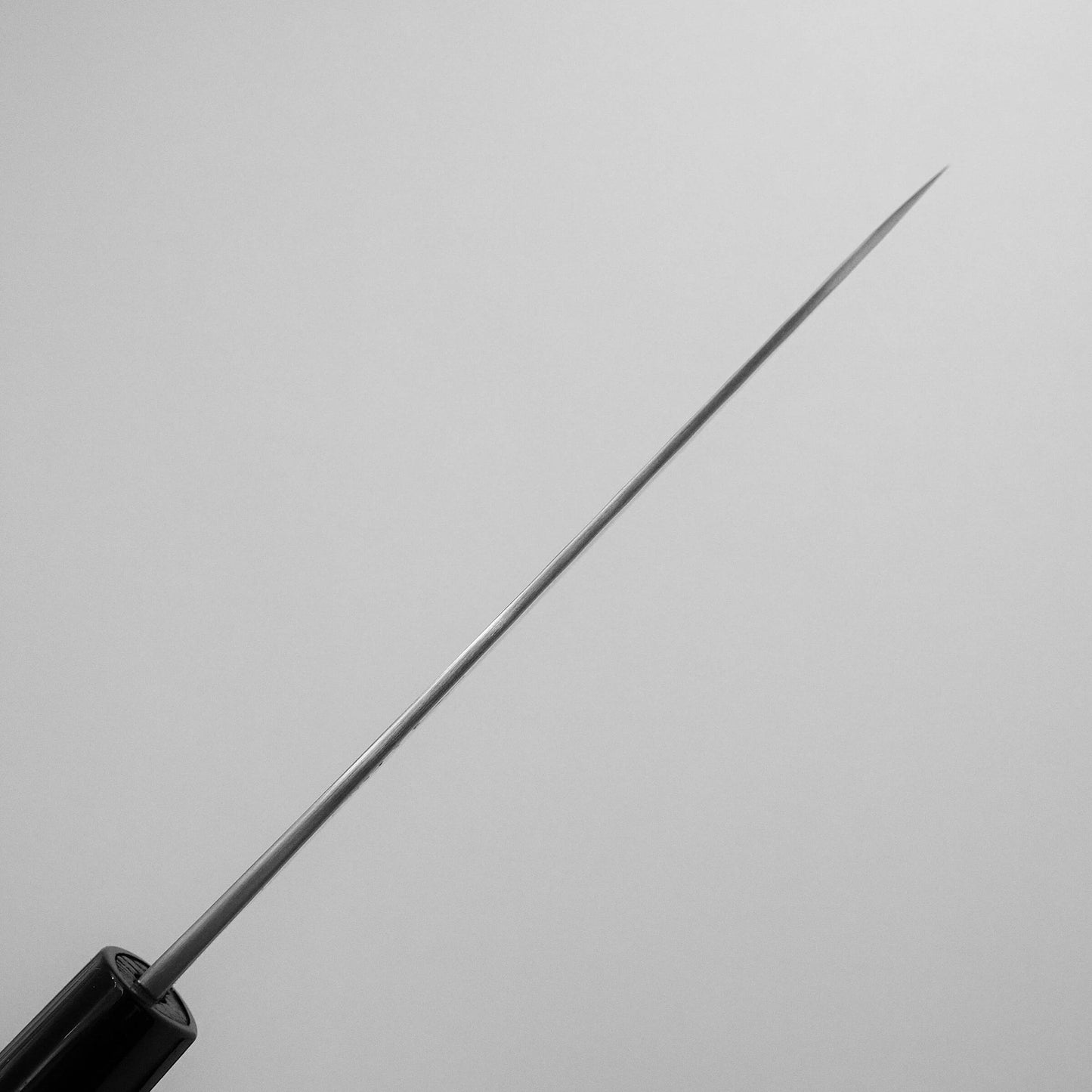 A close-up of a hypodermic needle attached to a syringe, set against a plain light gray background. The needle’s precision is reminiscent of the Yoshikane tsuchime SKD santoku 165mm by Yoshikane.