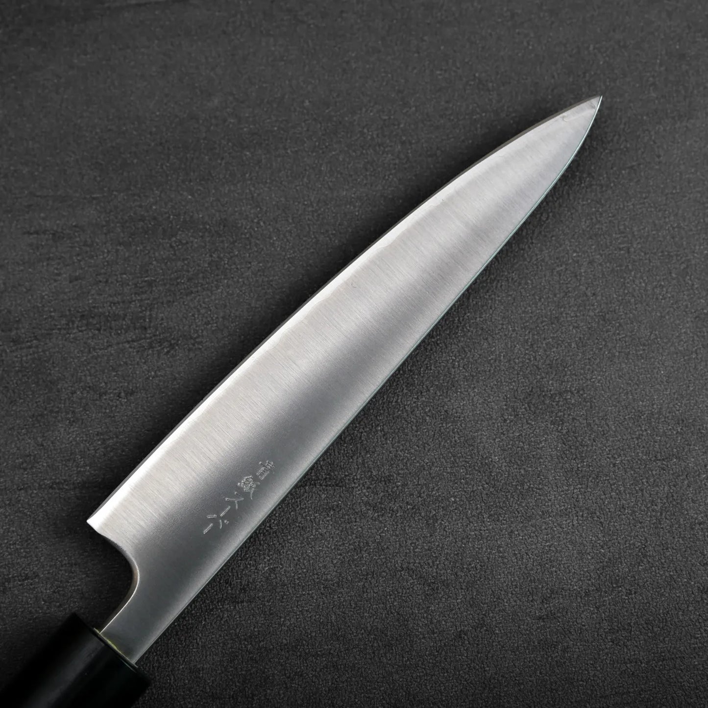 A petty knife with a black handle is shown, highlighting the blade and handle design in close detail.