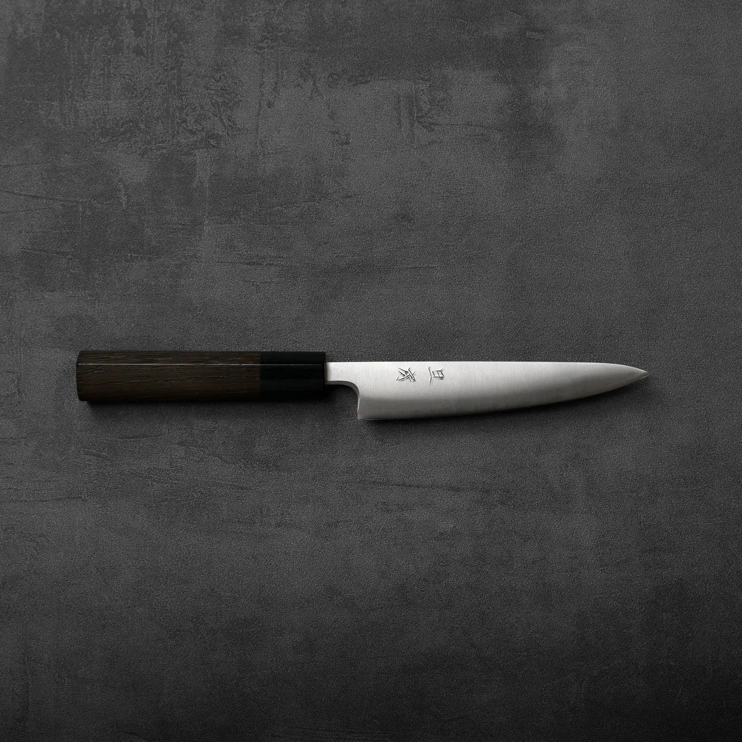 Petty knife with a dark handle and silver blade, showing subtle contrasts in materials and finish.