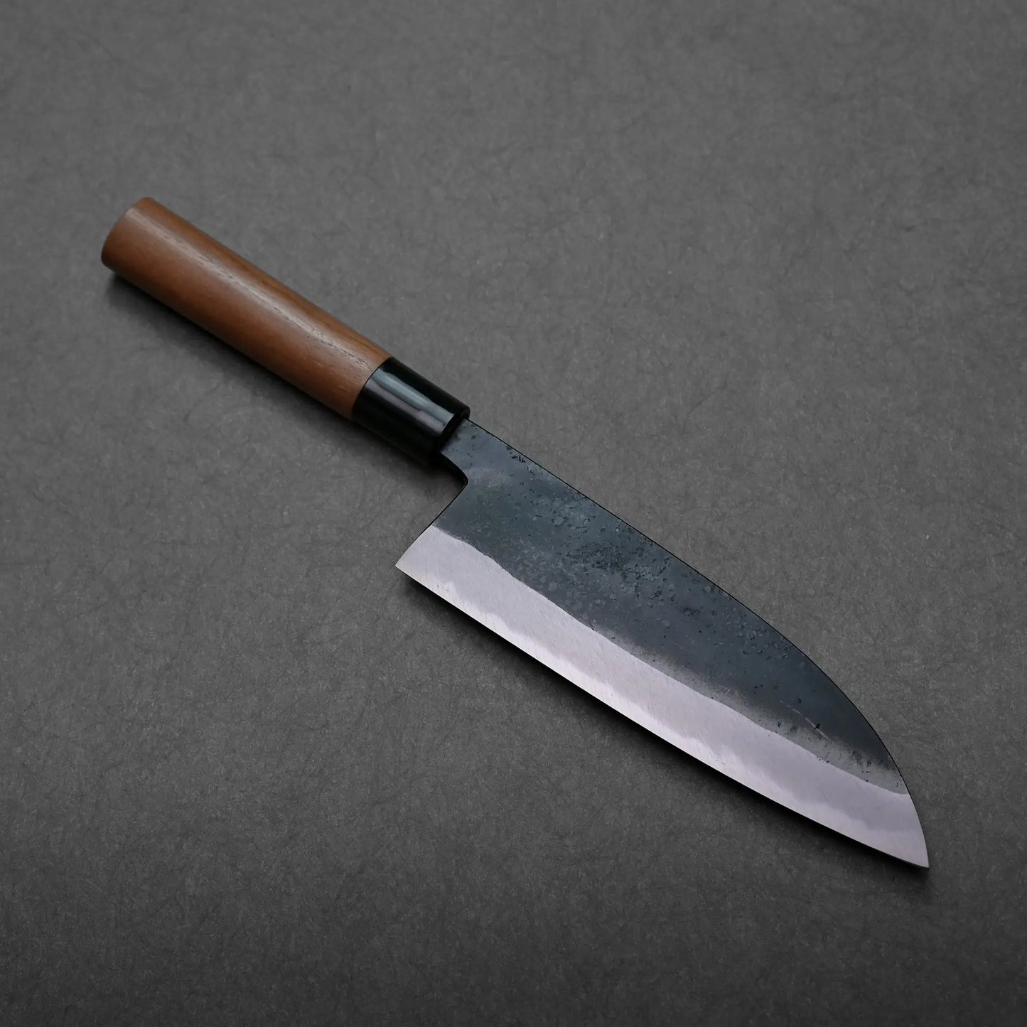 Wooden-handled Japanese knife by Daisuke Nishida with a dark, curved blade, likely a gyuto.