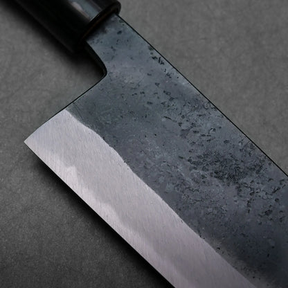 Close-up showing dark, textured finish on the blade of a Japanese knife; blade shape not fully visible in this view.