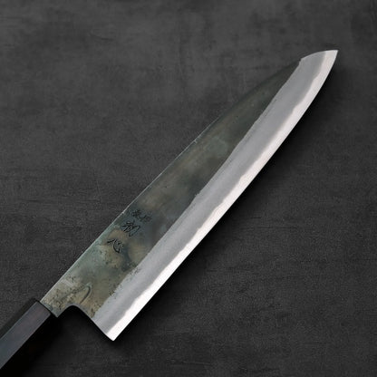 A gyuto with a dark handle is shown, highlighting the contrast of its handle against the blade.