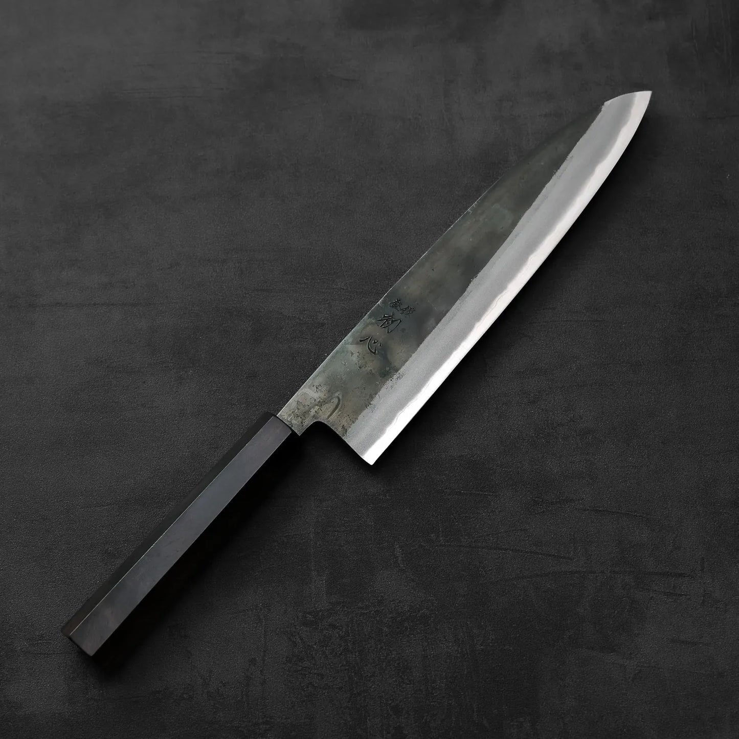 A Hatsukokoro Kurosagi AS gyuto 240mm with a dark handle is shown, highlighting its blade and grip.